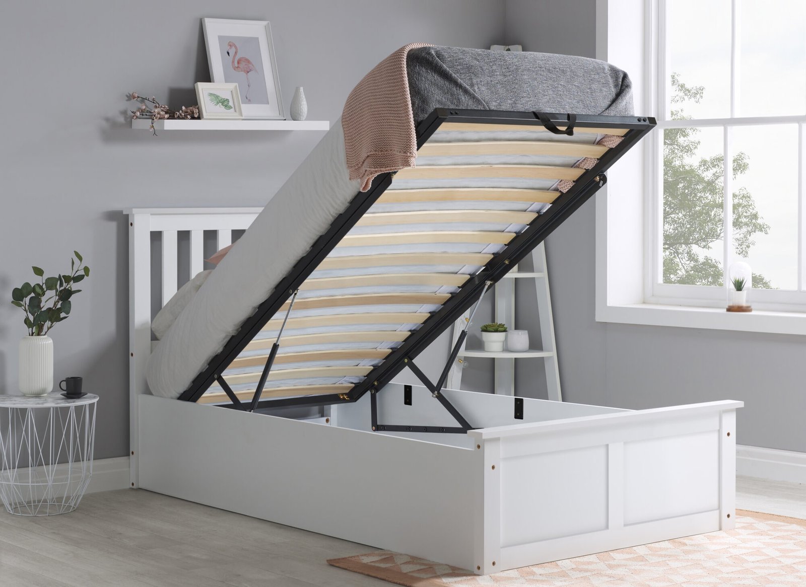White ottoman bed in a small bedroom with the base lifted to show the storage